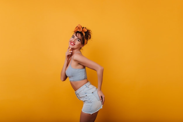 Blissful dark-haired young woman playfully posing on yellow space