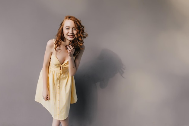 Blissful ginger girl in yellow dress posing in studio Portrait of happy redhaired woman expressing positive emotions