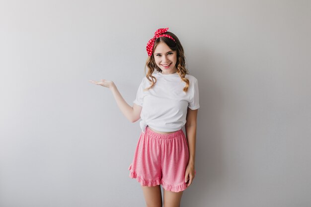 Blissful lady wearing pink shorts expressing positive emotions. Portrait of jocund european woman isolated.