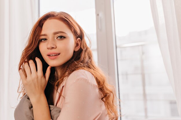 Blissful red-haired girl posing in weekend morning. Joyful ginger lady