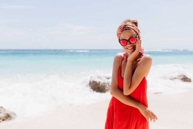 Blissful tanned woman posing with beautiful smile in the beach