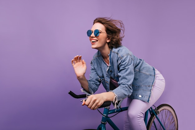 자전거에 포즈 캐주얼 재킷에 행복 한 여자. 자전거를 타고 스파클 안경에 감정적 인 짧은 머리 소녀.