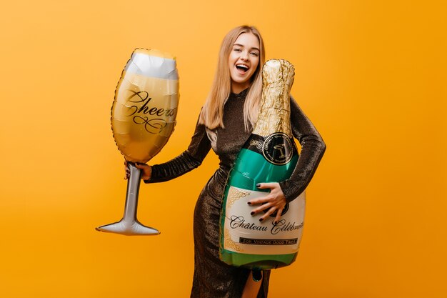 Blithesome caucasian woman funny posing with champagne. Well-dressed amazing woman celebrating birthday and fooling around at party.