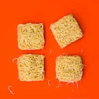 Foto gratuita blocchi di spaghetti istantanei disposti su una superficie arancione brillante