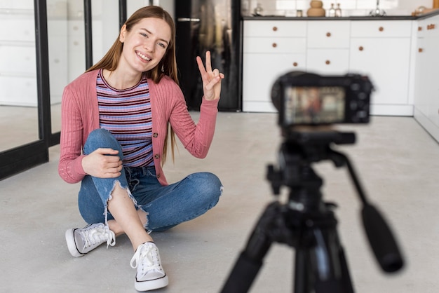 Free photo blogger doing peace sign in front of camera