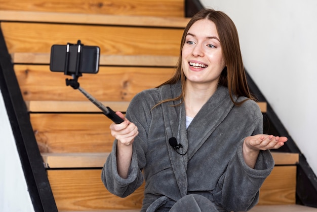 Blogger in dressing gown and recording with smartphone