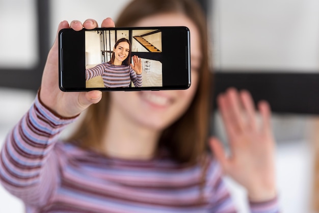 Blogger holding phone and recording herself waiving