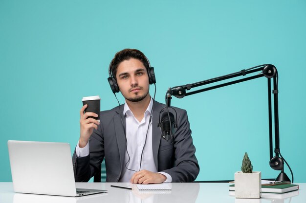 Blogger journalist cute handsome young guy in grey suit recording video with coffee cup