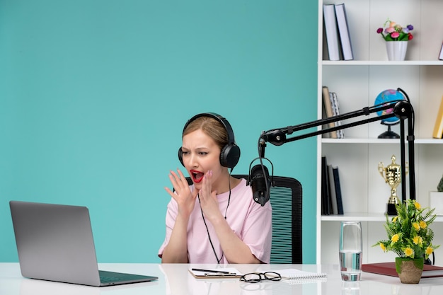 Blogger journalist cute young blonde girl recording video on computer screaming