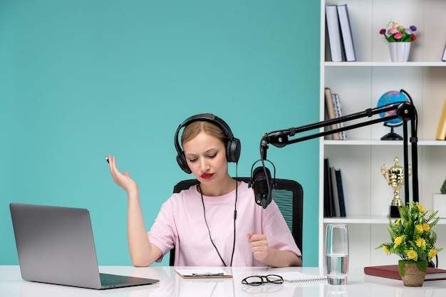 Blogger journalist young cute blonde girl recording video on computer in office waving hands