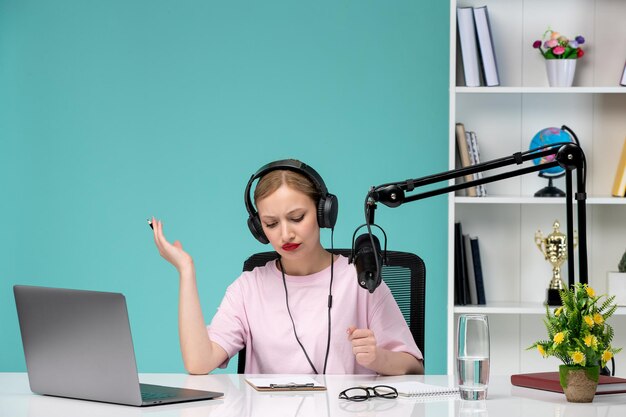 Blogger journalist young cute blonde girl recording video on computer in office waving hands