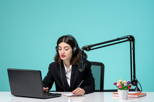 Blogger journalist young cute girl in black blazer recording speech on camera writing