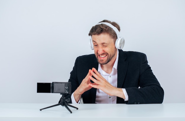 Free photo blogger man is posing to his mini camera by listening music on headphone on white background