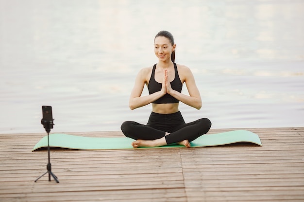 Free photo blogger practicing advanced yoga by the water