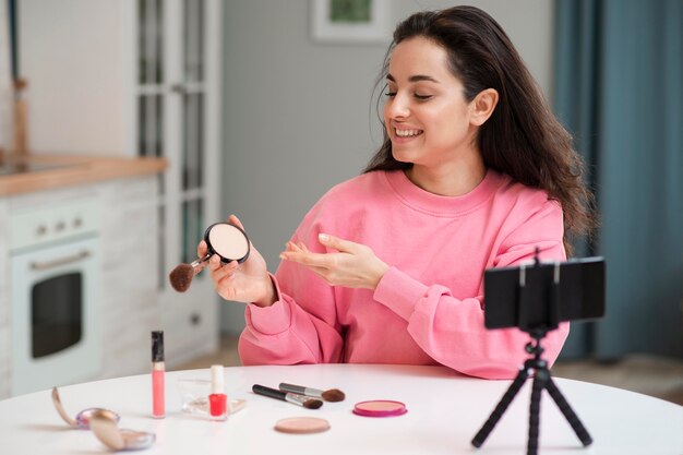 Blogger recording video with make-up accessories