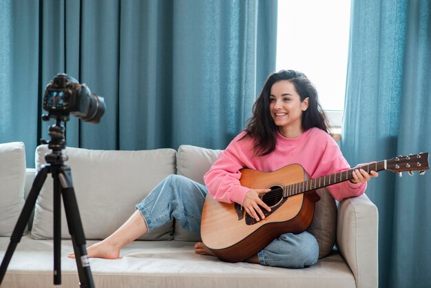 Blogger sitting and playing the guitar on the couch