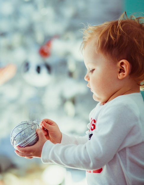 Free photo blond boy plays with christmas tree