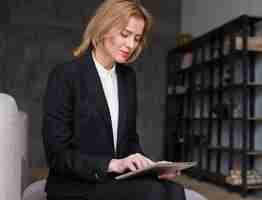Бесплатное фото Блондинка деловая женщина сидит и с помощью планшета