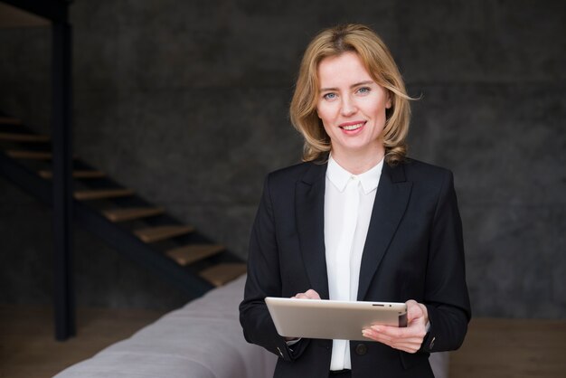 Blond business woman in suit using tablet