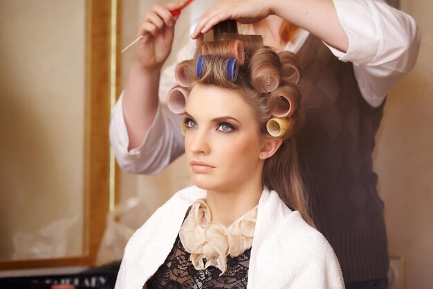 Blond female in hair salon. Hairdresser on background