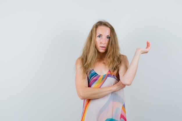 Blond female looking at camera in summer dress and looking puzzled 