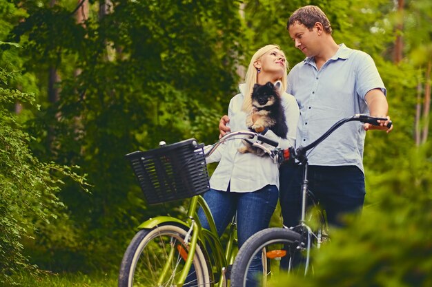 Blond female and a man on a bicycle ride in a park.