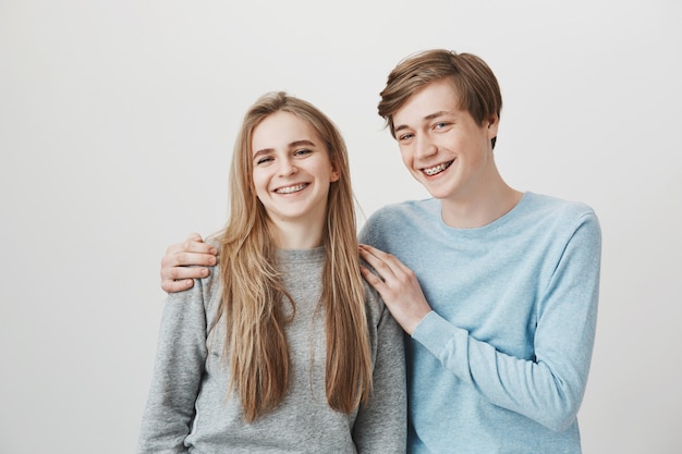 Blond girl and guy with braces laughing, smiling and hugging