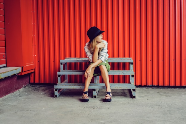 Blond girl in a hat. Street photo. A beautiful girl wearing casual clothes is smiling mysteriously. Vintage style