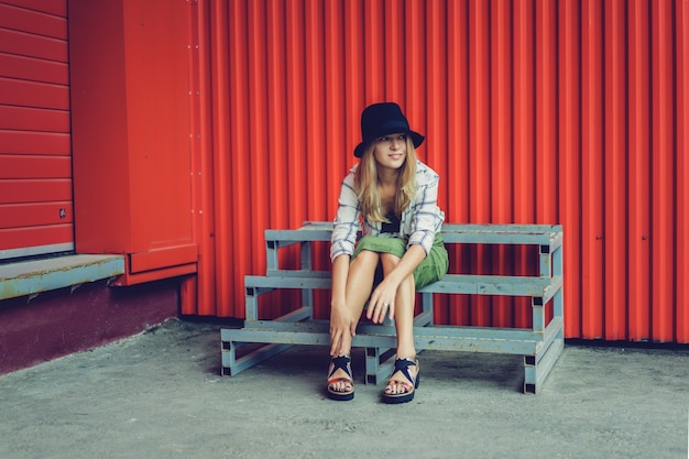 Blond girl in a hat. Street photo. A beautiful girl wearing casual clothes is smiling mysteriously. Vintage style