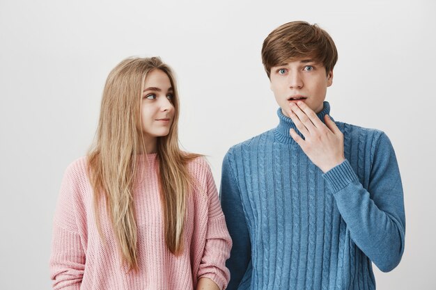 Blond girl look at guy gasping in surprise, gossiping