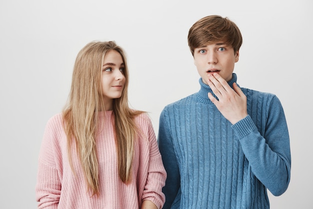 Blond girl look at guy gasping in surprise, gossiping