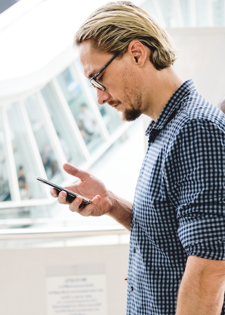 Uomo biondo che manda un sms sul suo telefono