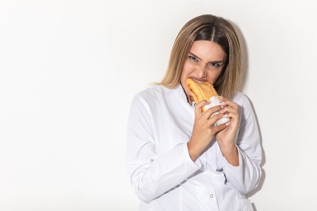 Блондинка модель кусает бутерброд как вампир и наслаждается.