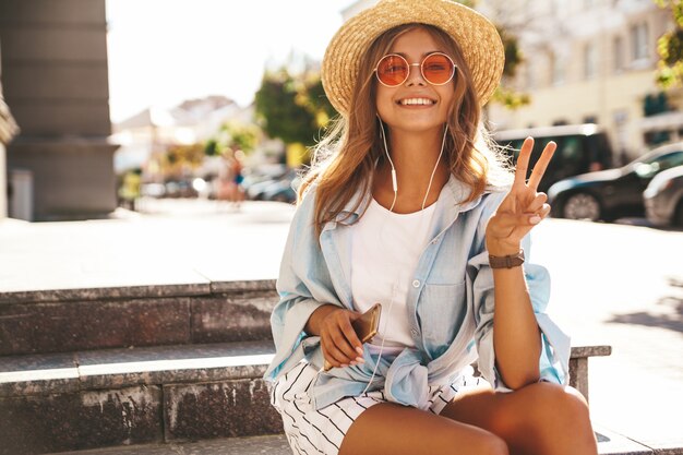 blond model in summer clothes posing on the street showing peace sign