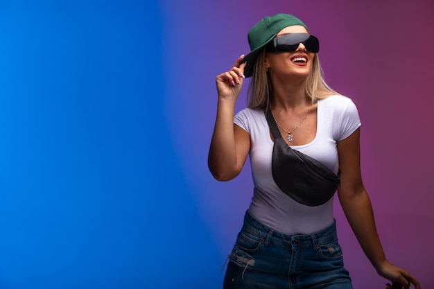 Foto gratuita la modella bionda che indossa cappello verde e occhiali da sole sembra positiva.