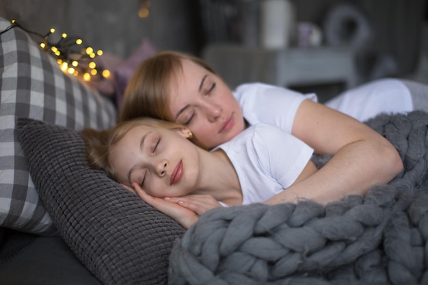 Блондинка мама и дочь подросток спят обнять на кровати