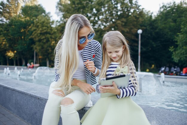 Blond mother teaching her daughter a tablet