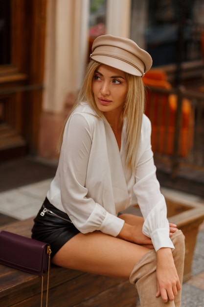 Блондинка сексуальная европейская женщина в модной осенней кепке позирует на открытом воздухе