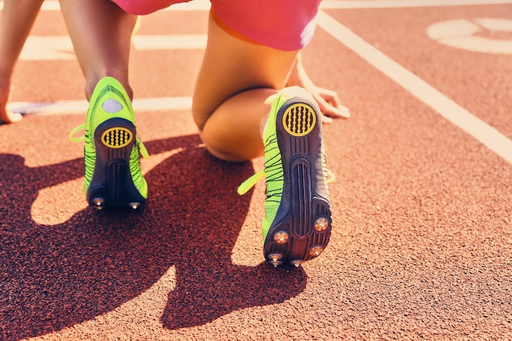 Free Photo blond sporty female runner to quick start position on a stadium.