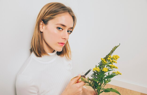 Blond woman cutting flowers with scissors