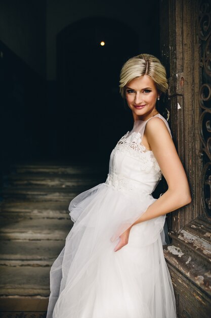 Blond woman dressed as a bride leaning on a door