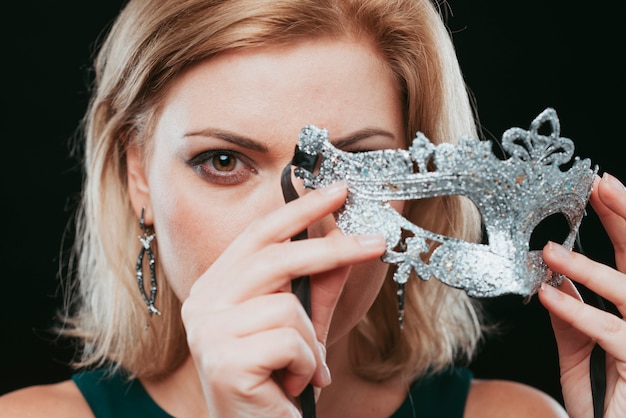 Бесплатное фото Блондинка держит серебряную маску в руке