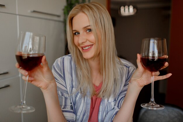 금발 여자는 그녀의 자신의 부엌에 두 잔의 레드 와인을 tases.