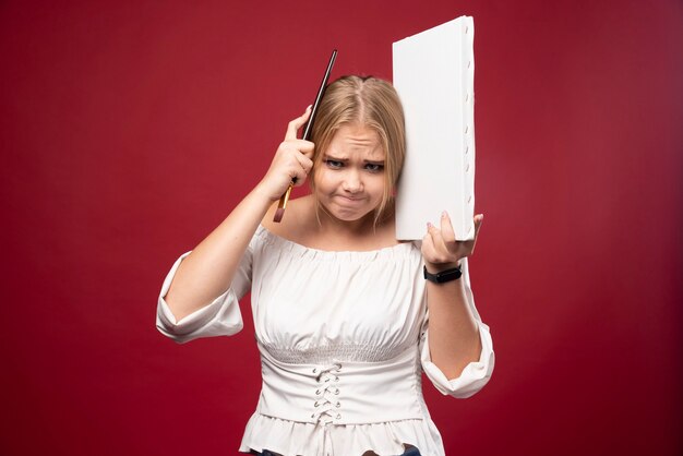 Blonde art master working on canvas with a paint brush and looks confused.