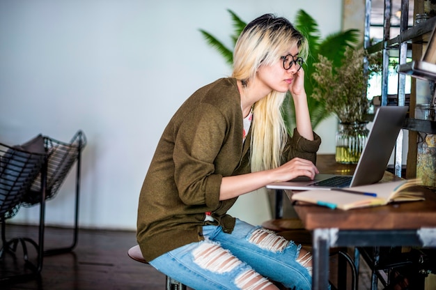 Free photo blonde asian woman working on a laptop