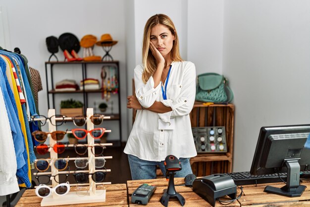 Blonde beautiful young woman working as manager at retail boutique thinking looking tired and bored with depression problems with crossed arms