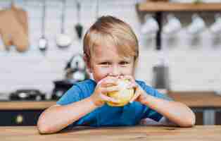 Free photo blonde boy eating an apple