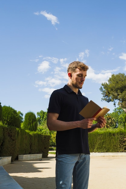 Free photo blonde boy reading in the park