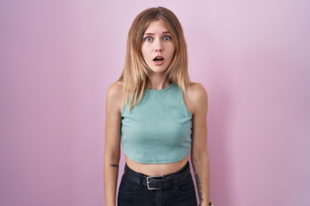 Free photo blonde caucasian woman standing over pink background afraid and shocked with surprise and amazed expression fear and excited face