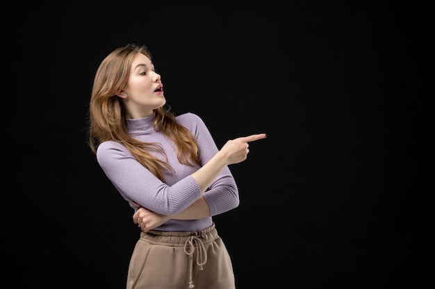 Ragazza bionda concentrata che punta qualcosa sul lato sinistro al buio